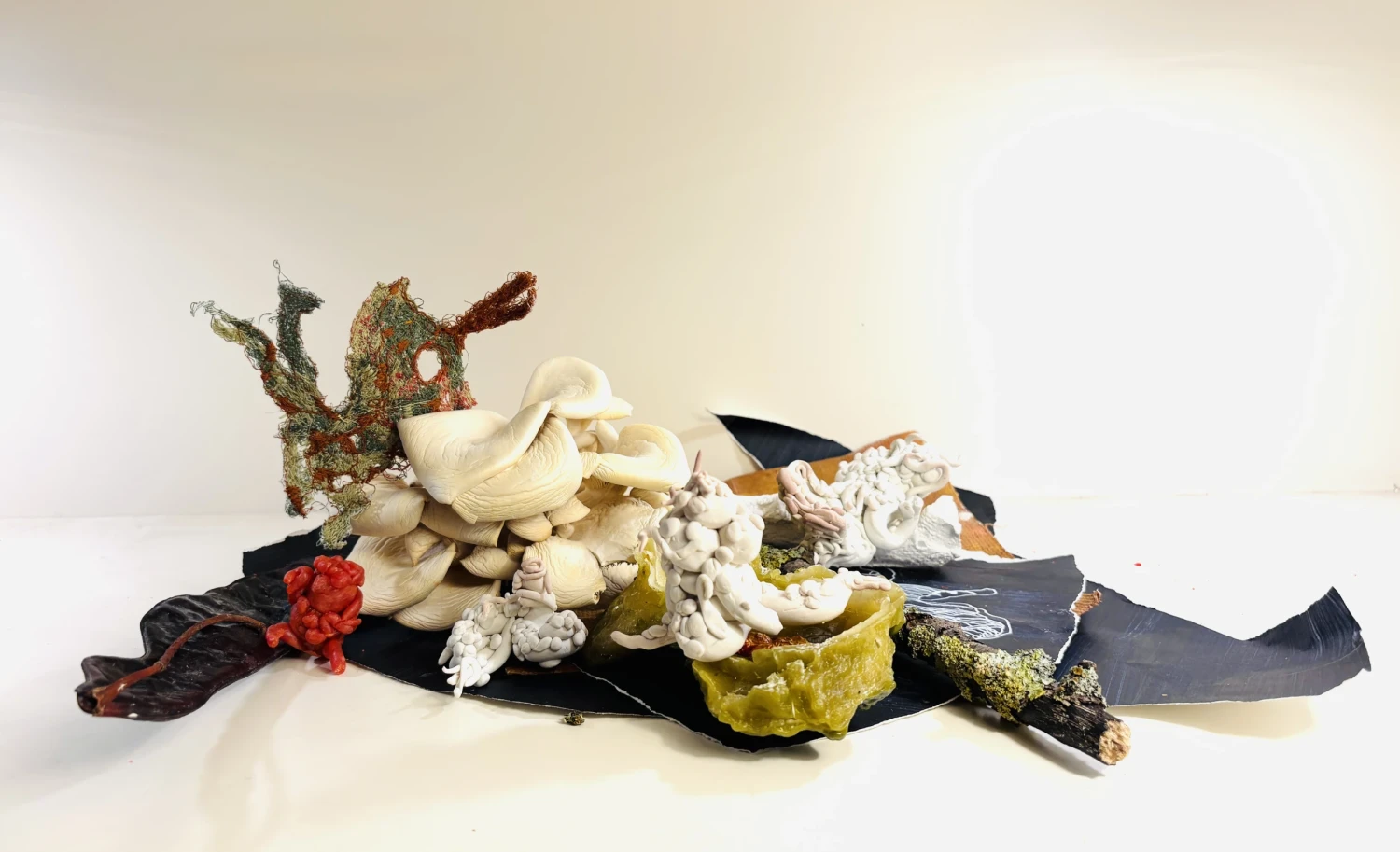 *Against Purity*, polymer clay, Herculite cast of branch, oyster shells, fragmented dyed Jesmonite, red wax sculpture, dehydrated oyster mushroom, shell, free embroidery, lichen twig, embroidery material dyed in a turmeric and copper carbonate wax mix, cast oyster shell in turmeric- and copper carbonate-infused wax, Posca drawing on acrylic-painted Fabriano paper, dimensions variable.