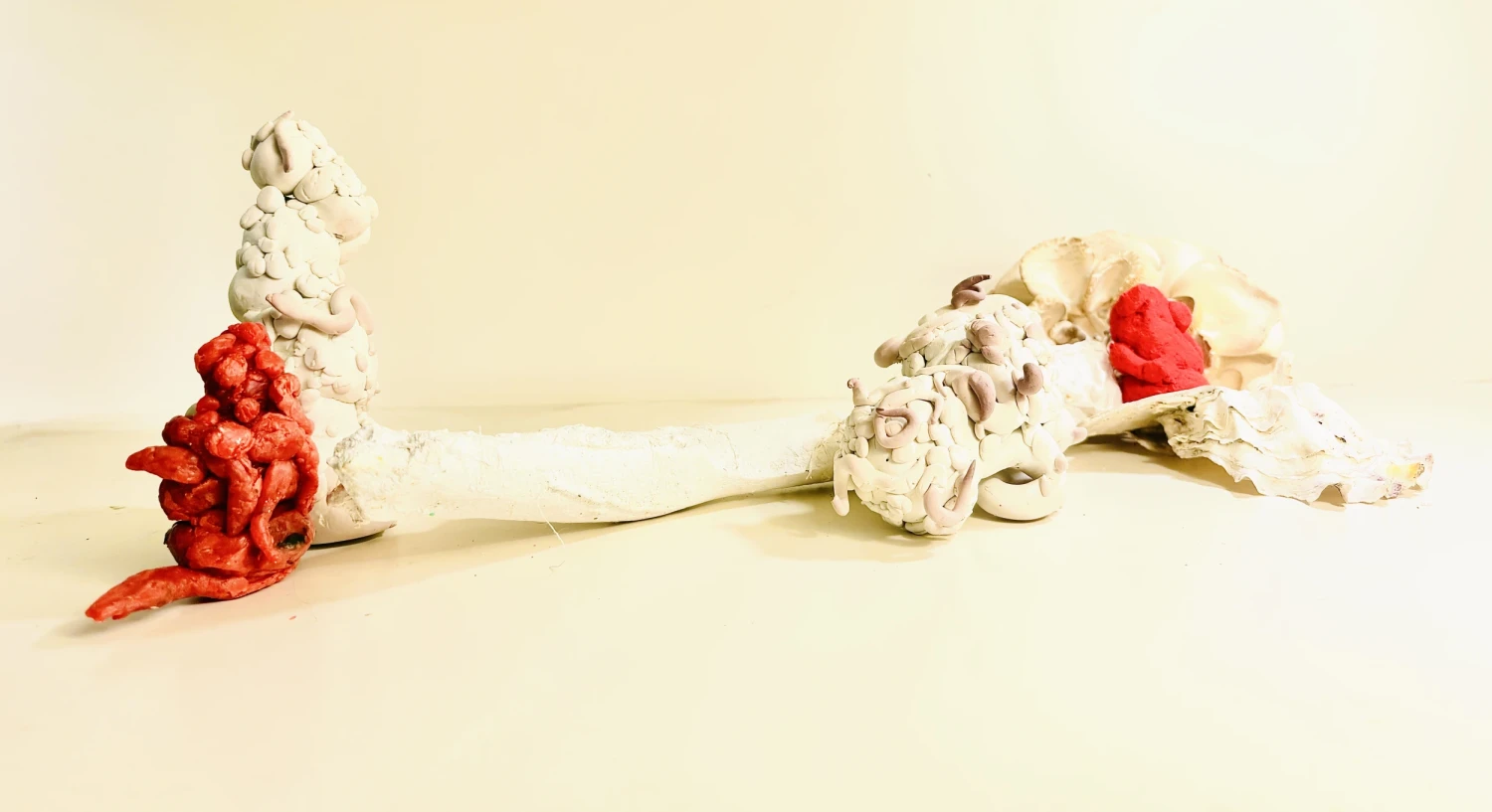 *In Praise of Weird Little Beings*, red wax, polymer clay, oyster shells, Jesmonite, Herculite cast of branch, dimensions variable.