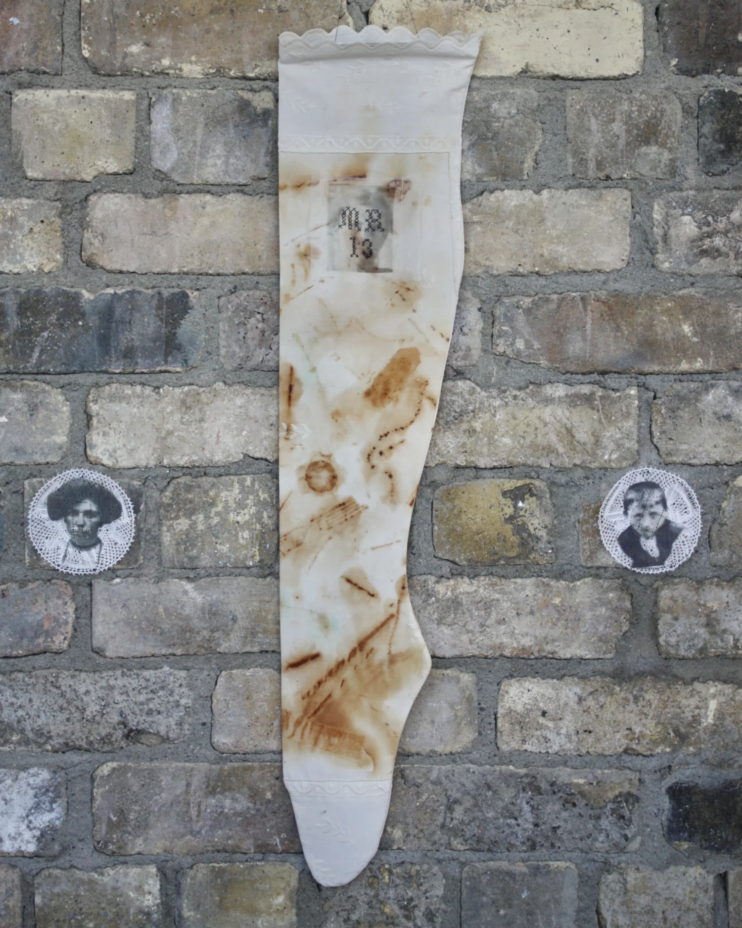 Rust dyed stocking with child's face, initials and age stitched with hair.
