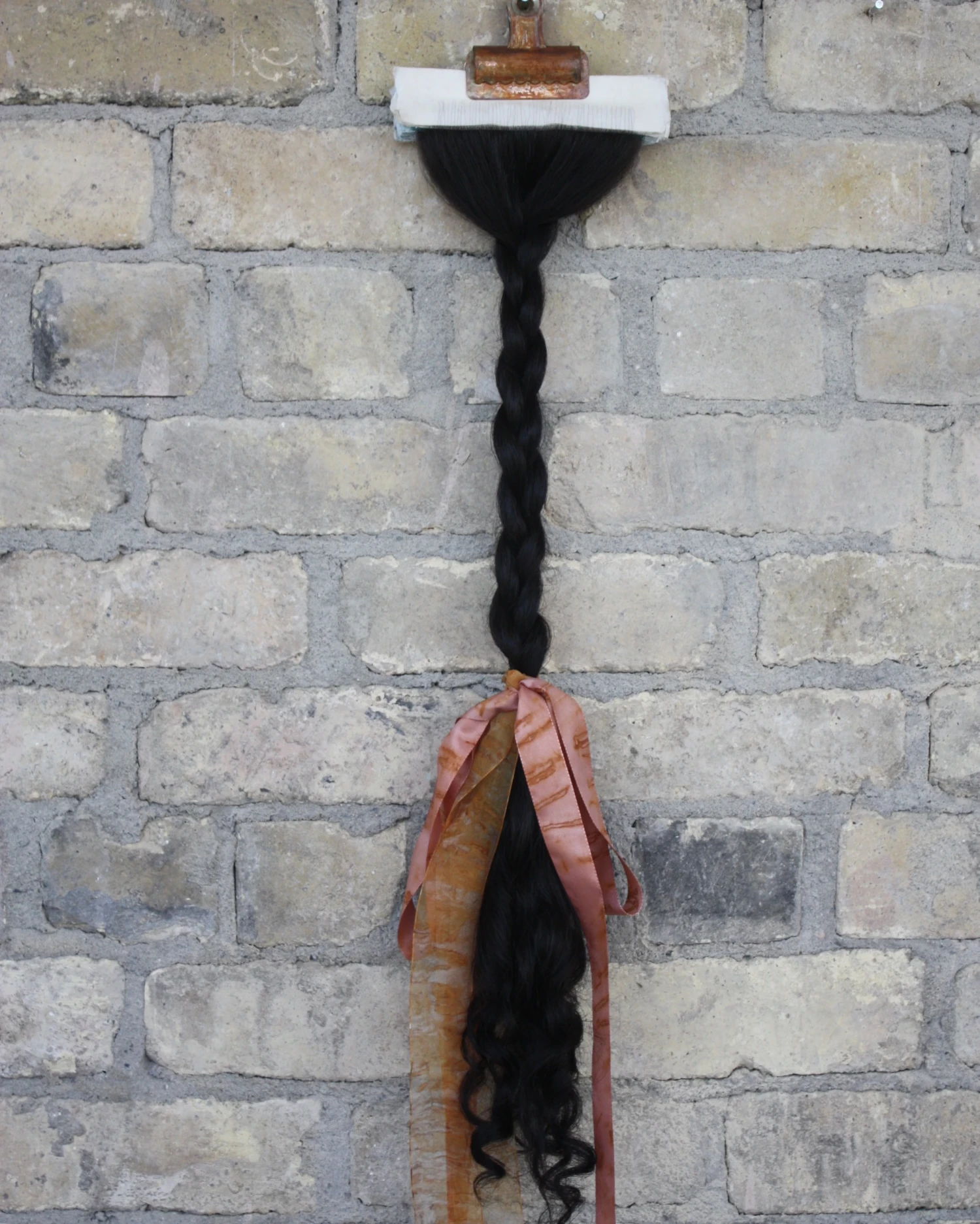 Collected human hair, rust dyed ribbon.