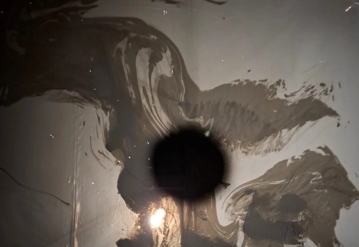 Ink floating in the water pool, lit from above with cast shadow, pool 120 x120 x 18 cm.