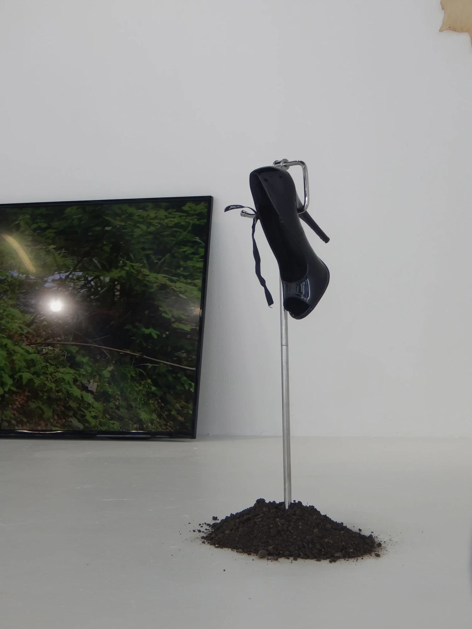 Installation view of *Sordid and Tender*, 2026, patent heel, toilet roll holder, dirt, ribbon, confetti, synthetic yarn.