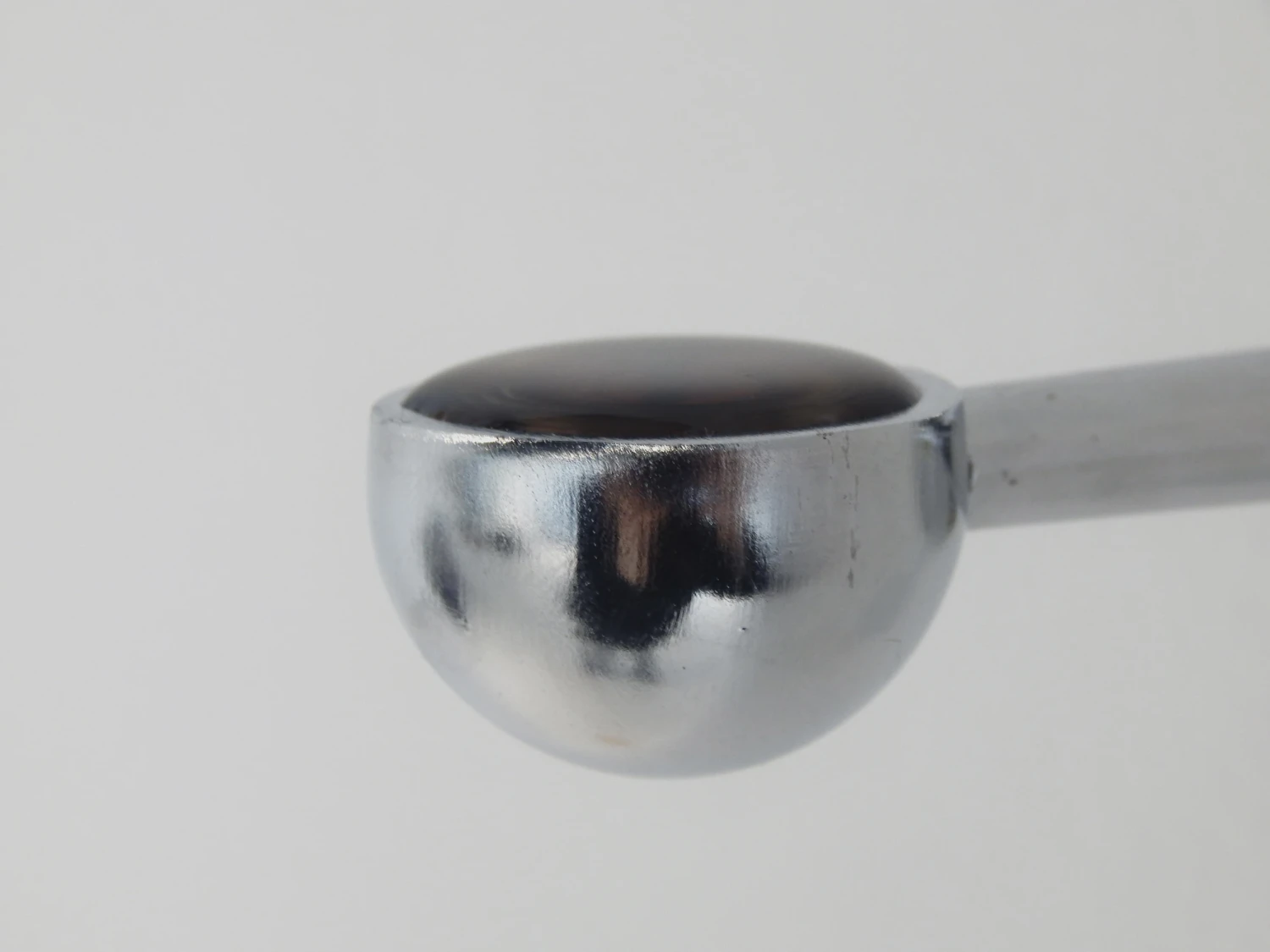 Detail view of *Let's go back to sleep*, 2026, round end brackets, screws, honey, four-year-old Kerry mountain water, Cretaceous-period amber segment.