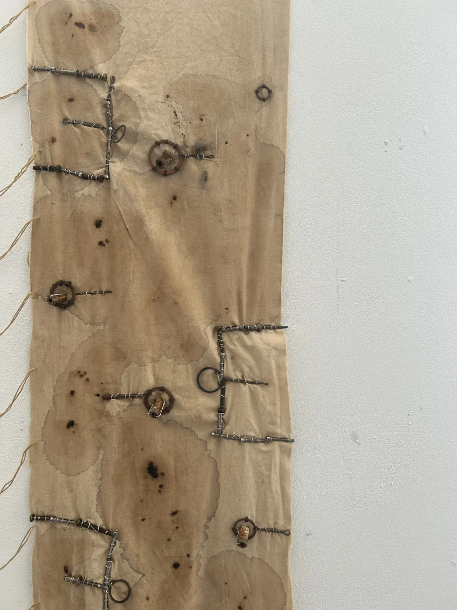 Close up of right wall hanging: hard materials stitched using wire and natural dye