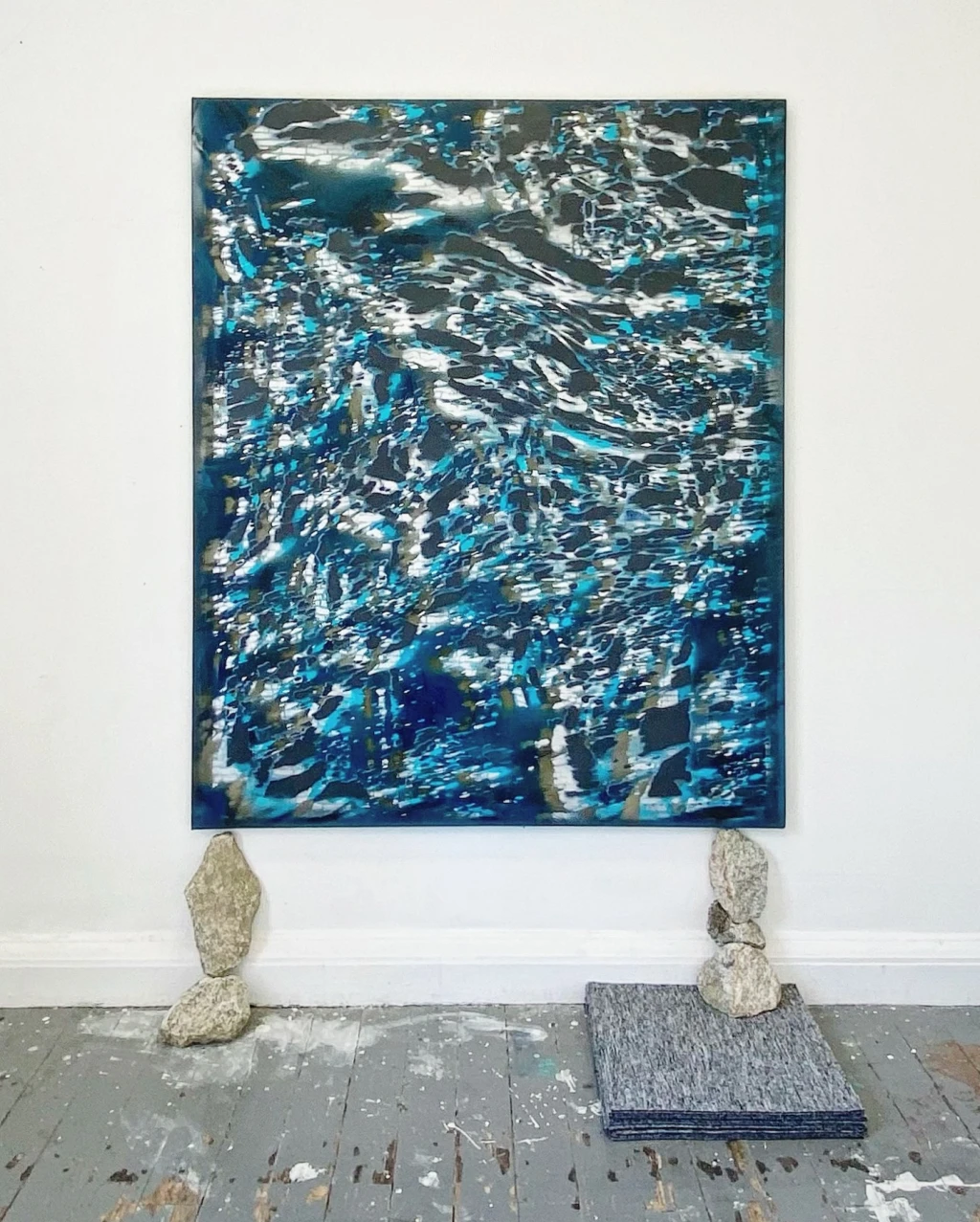 *The Compression of Everything We Meant by Time*, 2025, marble dust, acrylic, spray paint and pigment on canvas, granite rock and office carpet tiles, 145 x 170 cm.