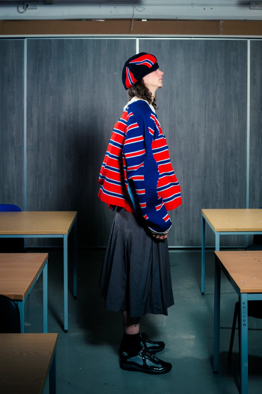 Danny in *Look 1*, Merino wool, Grilon and cotton moulded *Heart Jumper*, fully fashioned. Wool suiting coulottes with double pleated crotch. Styled with knitted Baker Boy hat.