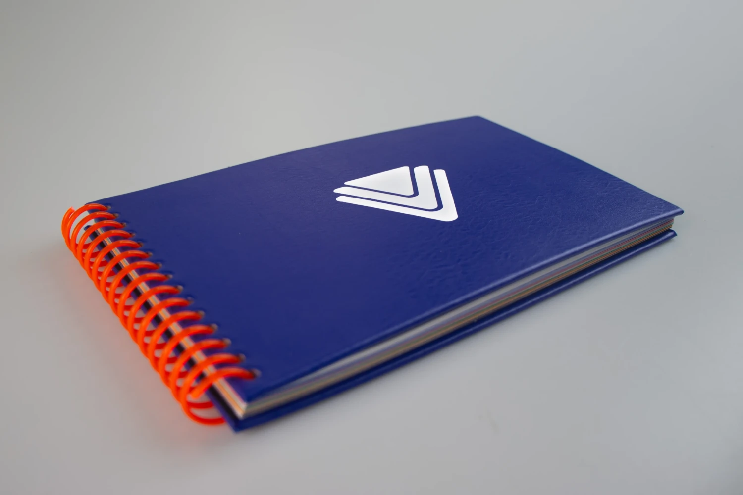 Publication spiral bound in blue leatherette with logo in white vinyl, 22.4 x 12.8 cm.