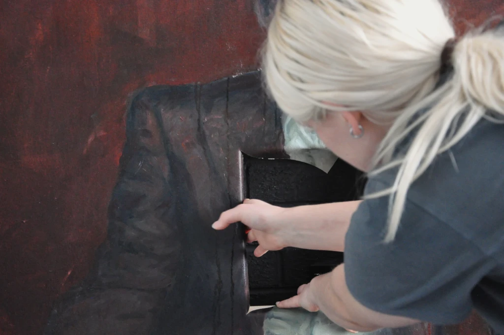 Tucking canvas behind the stretcher.