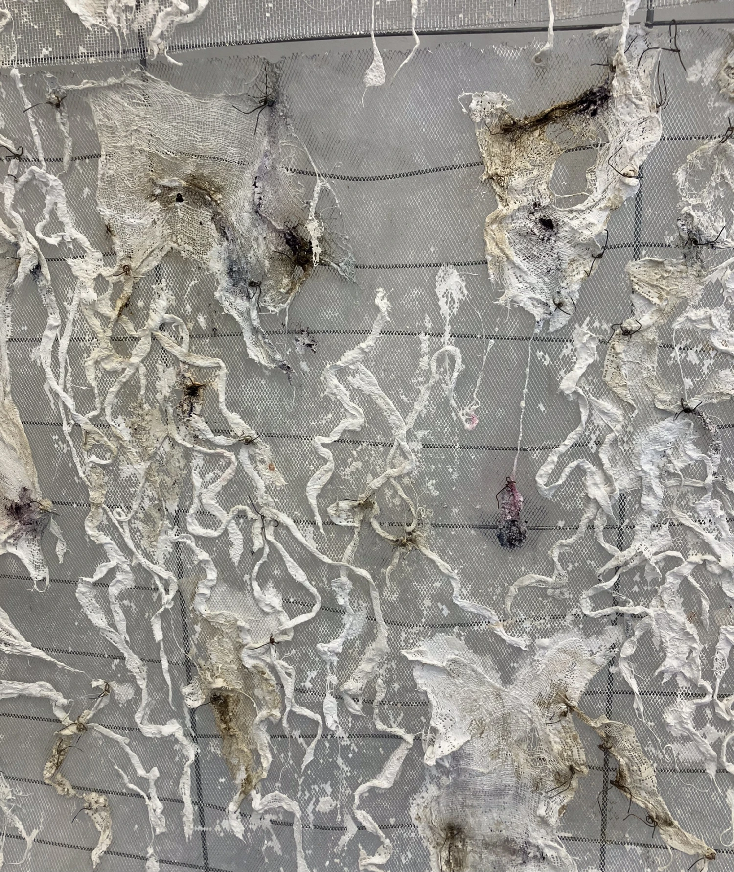 Close-up of wire mesh/ plaster bandage stained with acrylic high flow paints on hanging piece.