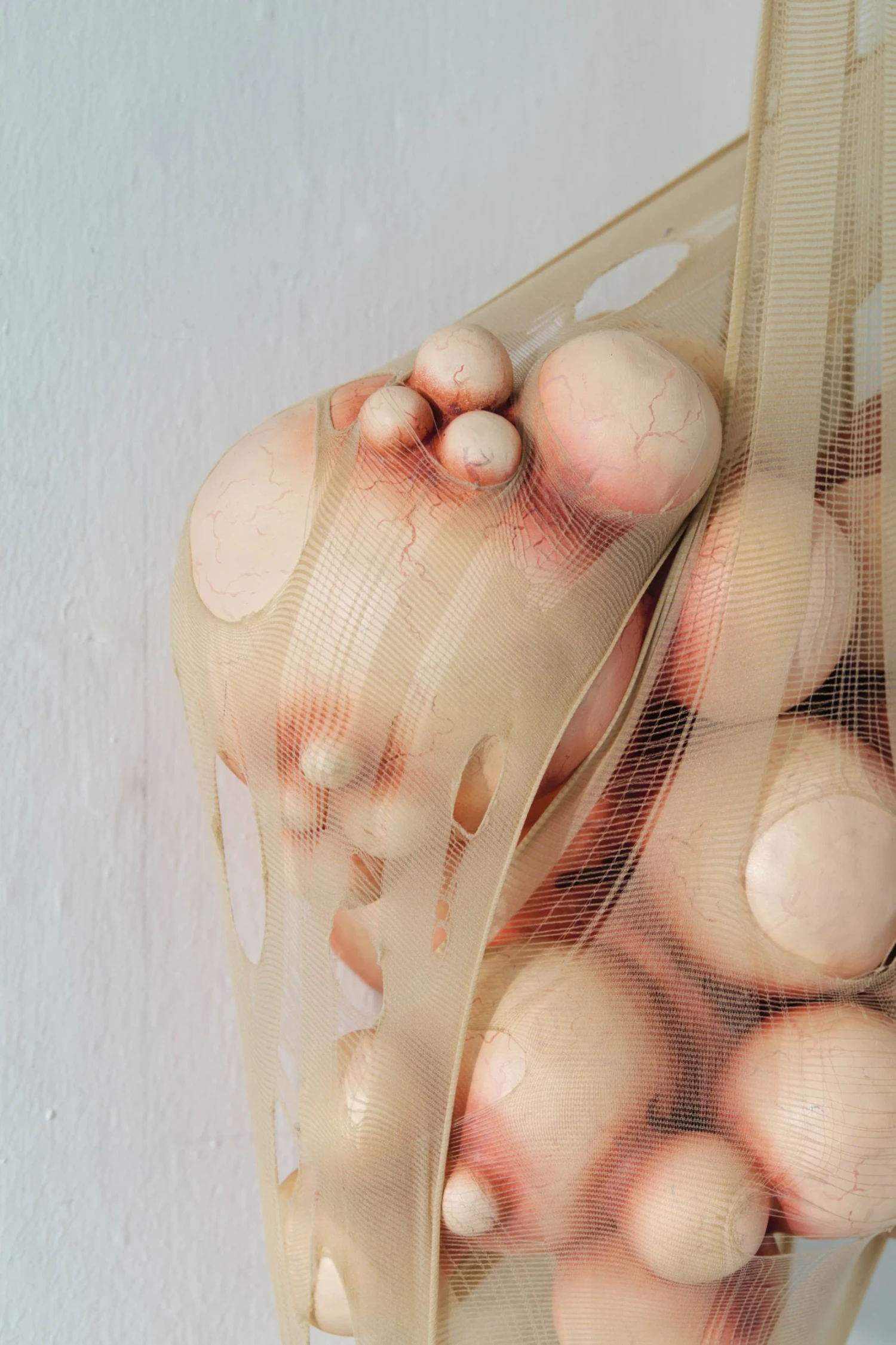 Untitled, ceramic, oil paint, nylon tights, metal hooks, 25 × 25 × 15 cm.