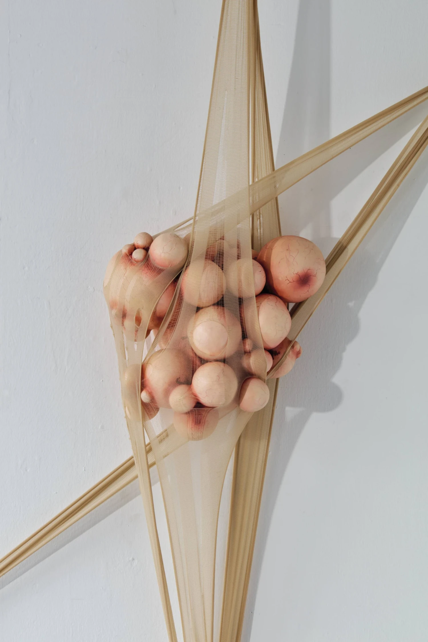 Untitled, ceramic, oil paint, nylon tights, metal hooks, 25 × 25 × 15 cm.