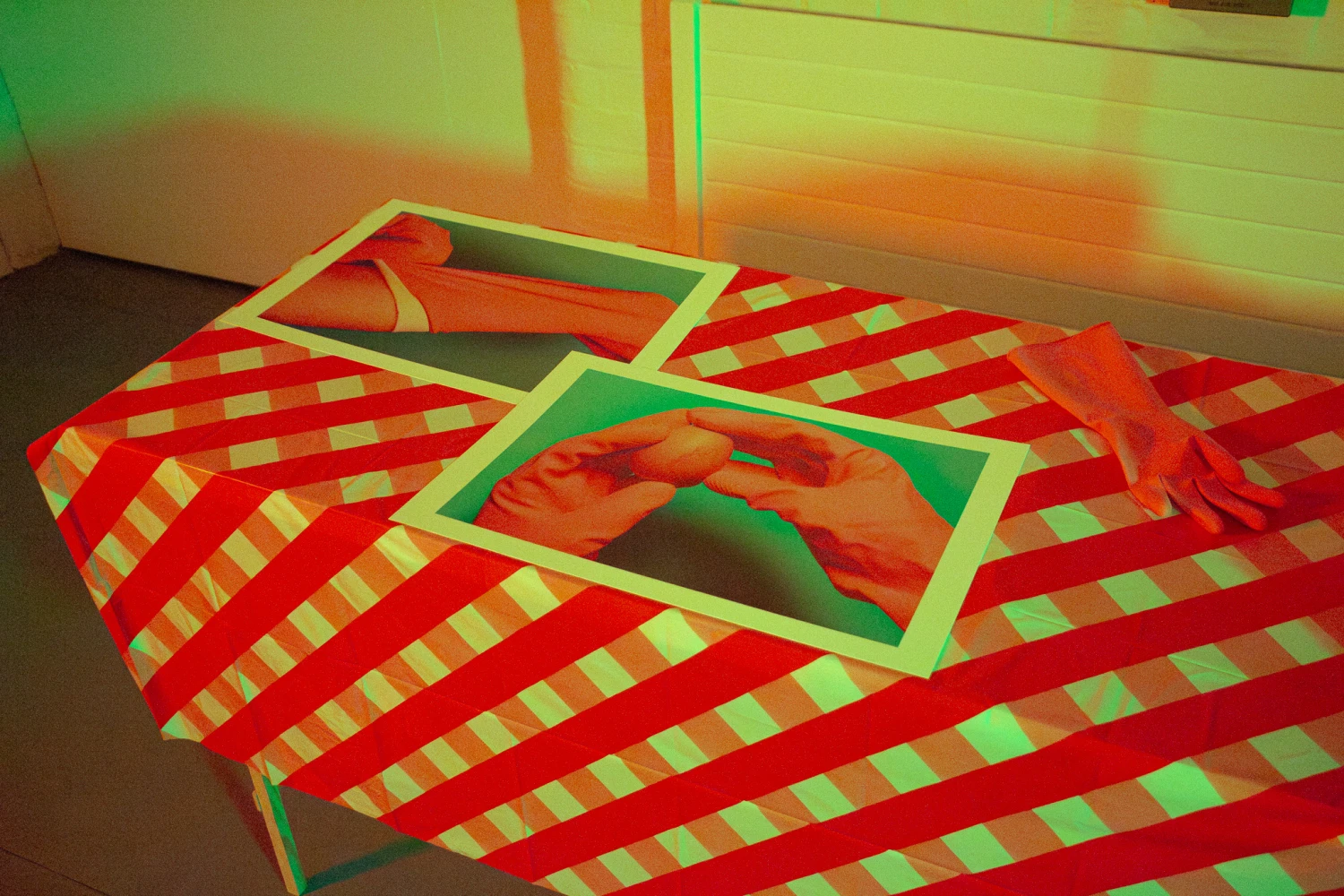 GUBBER ROVE, two Hahnemühle Metallic Rag archival paper prints lay on a table alongside a rubber glove, 29.7 x 42.0 cm. 
