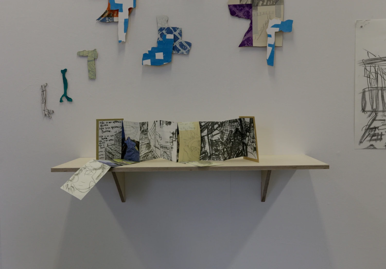 Wooden shelf at an accessible height for a wheelchair user with an accordion book on top.