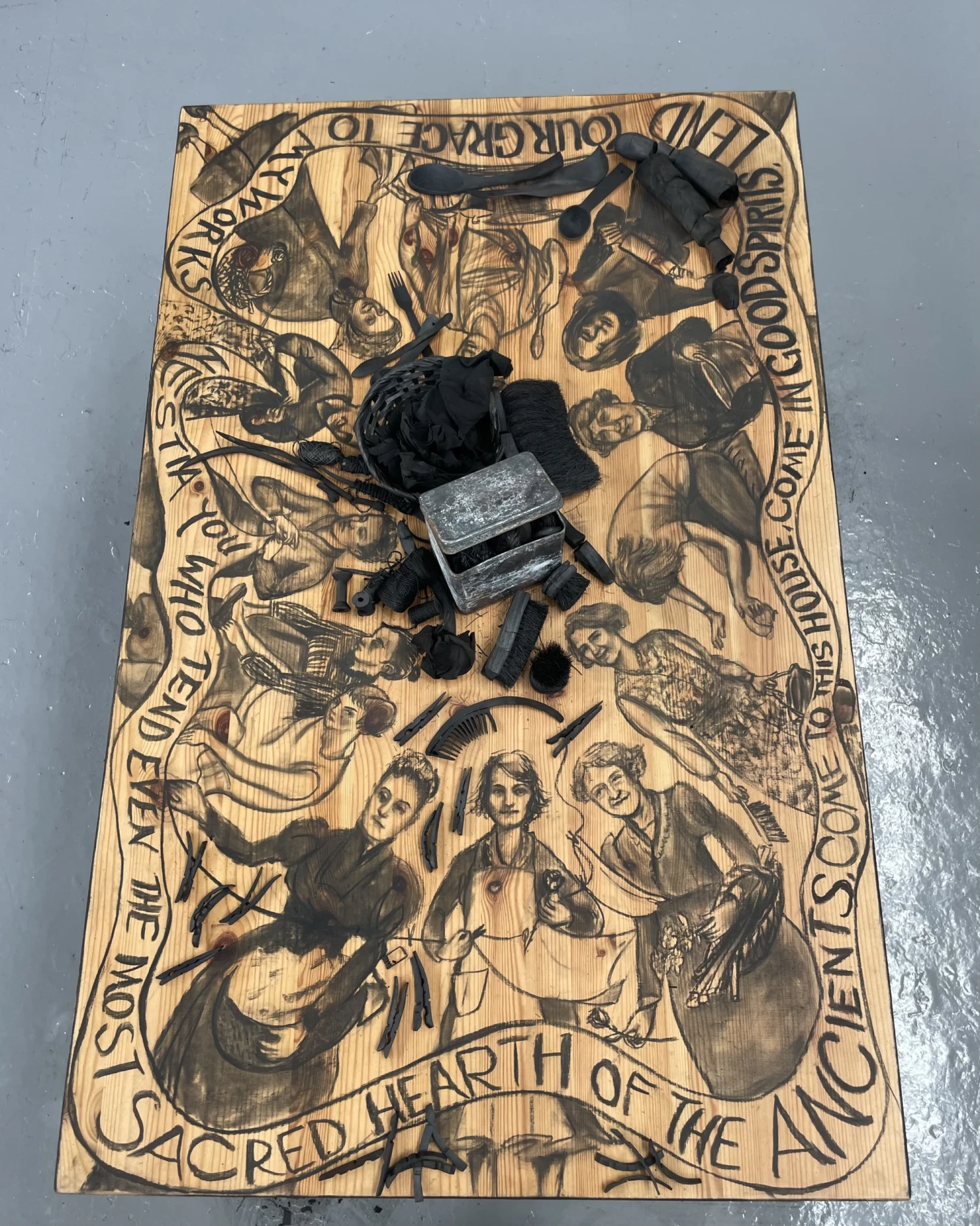 Detail view, *Hestia's Kitchen Table*, charcoal drawings, charcoal and tin caddy on wood table, 120 x 75 x 75 cm.