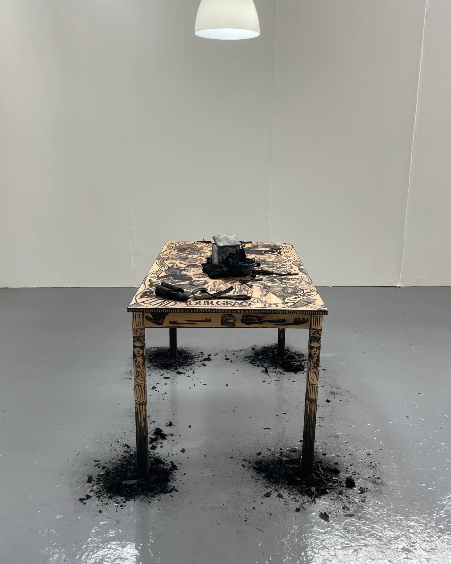 Installation view, *Hestia's Kitchen Table*, charcoal drawings, charcoal and tin caddy on found wood table, 120 x 75 x 75 cm, NCAD Works 2026.